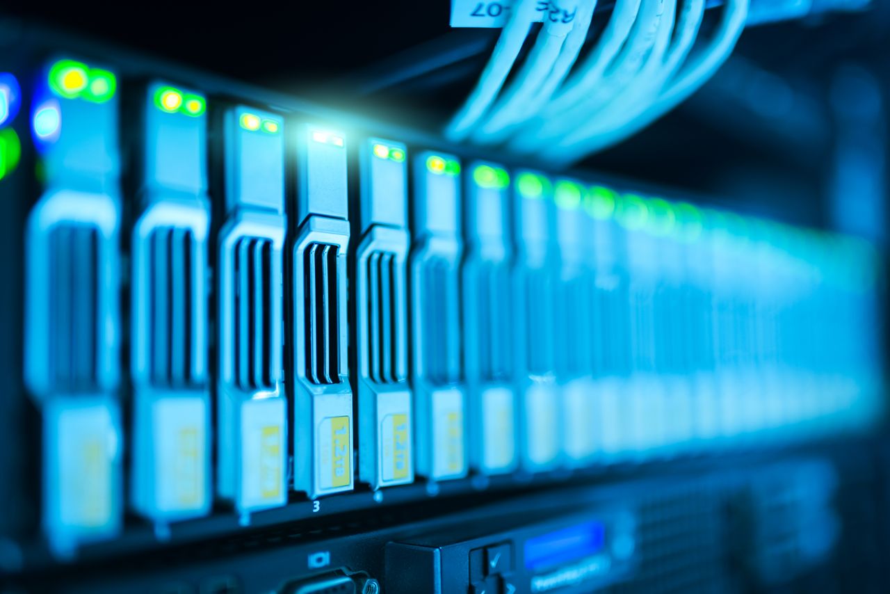 Services-01 Detailed image of a server rack with glowing lights in a modern data center.